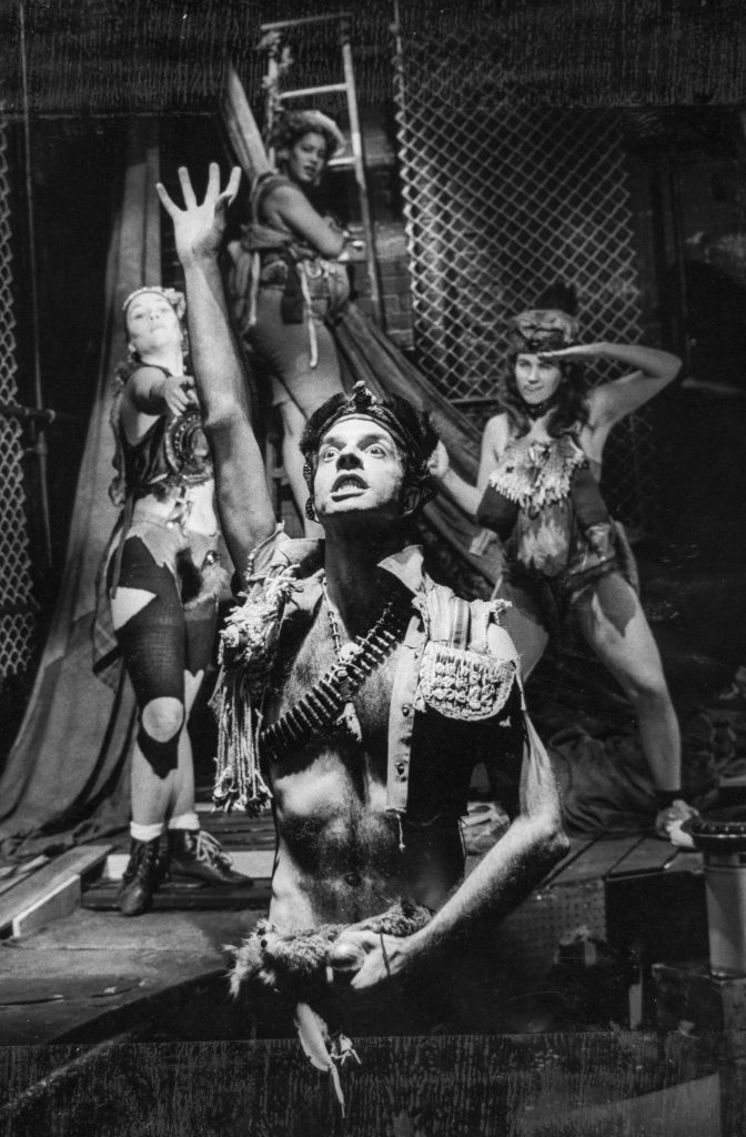 James Tait dressed as the Emperor with a bullet belt strapped around his bare chest, Holly Coles and Randi Helmers saluting behind him as Tabby Johnson fearfully climbs a ladder.