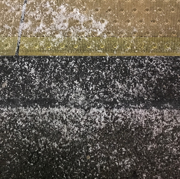 Snow on a railway platform and the raised edge near the track.