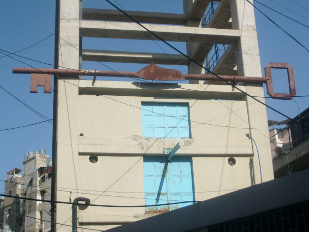 a huge rusted key mounted on the side of a building in Shatila refugee camp